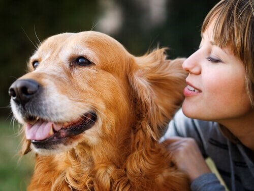Frau flüstert ihrem Hund ins Ohr